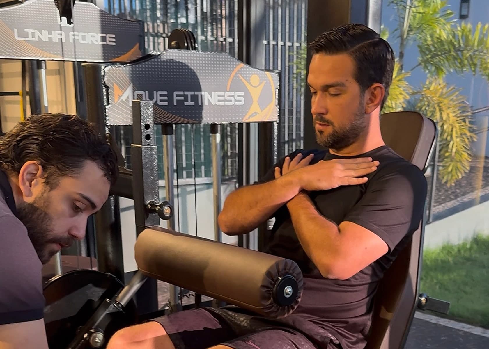 Personal trainer do Via Move orientando um aluno em máquina de força na sala de performance.