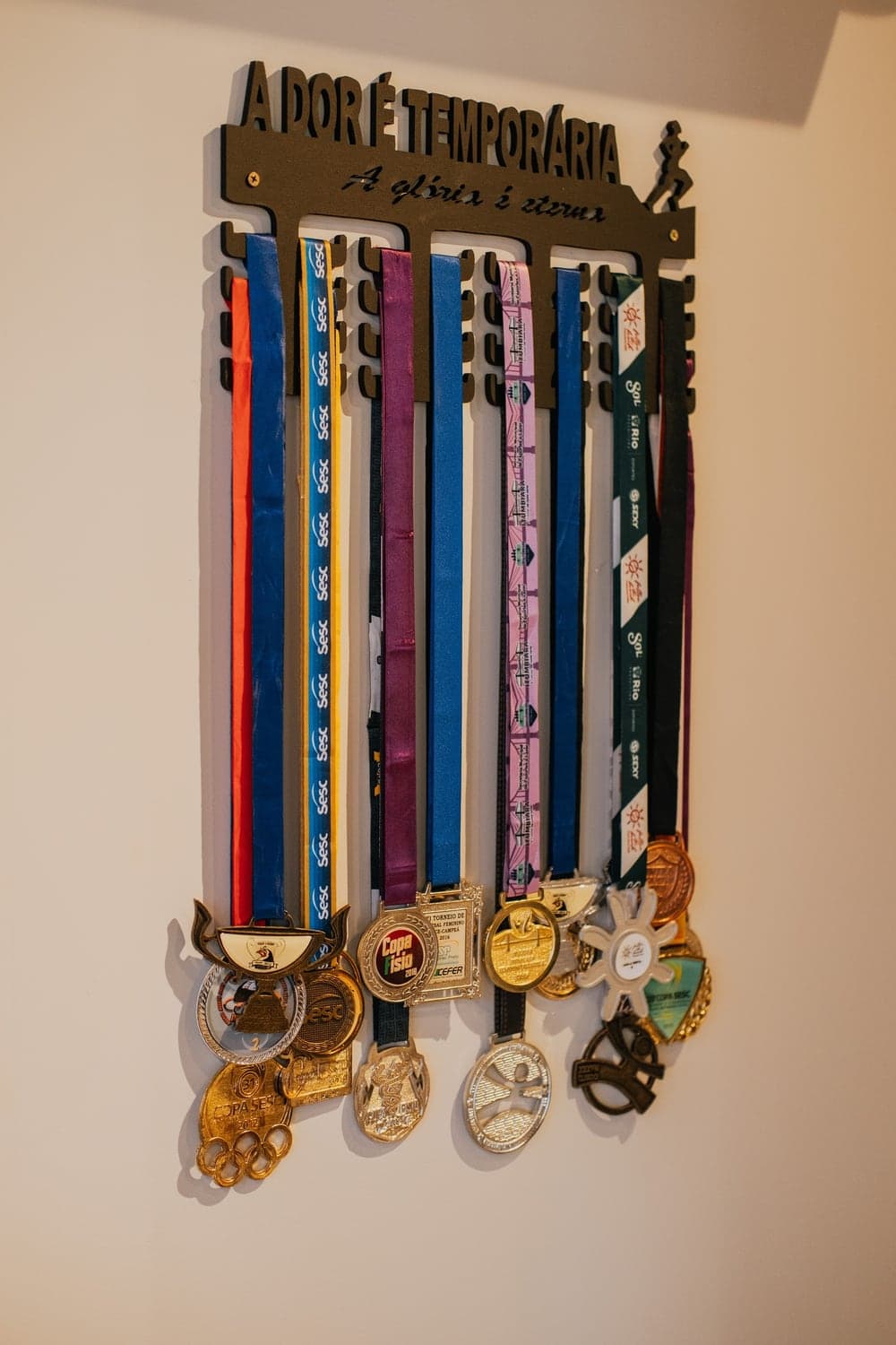 Parede de medalhas do Via Move sob a frase “A dor é temporária”.